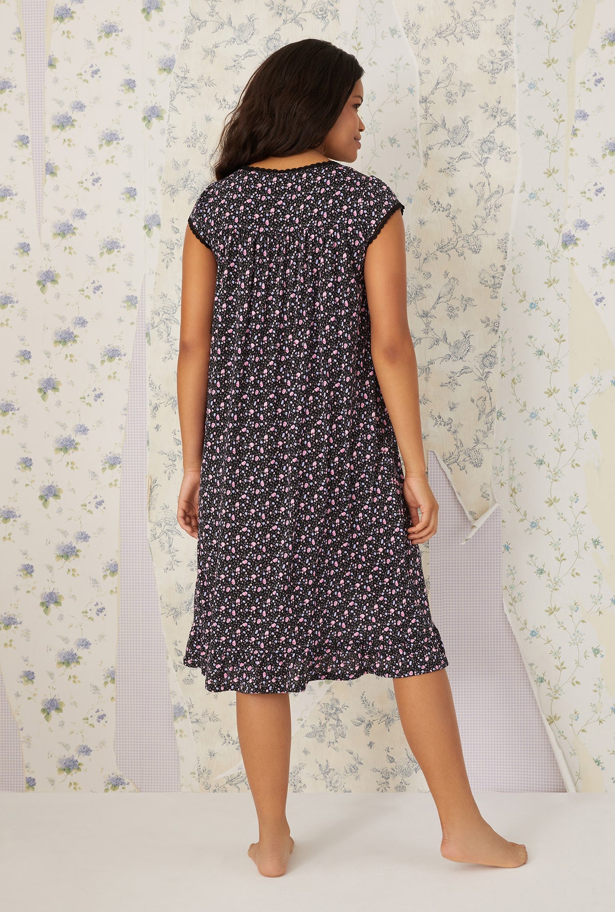A lady wearing black cap sleeve cotton modal waltz knit nightgown with night blooms print.
